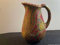 Full view of ceramic pitcher showing detailed floral pattern and curved handle.