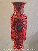 Front view of red cinnabar carved vase showing detailed figures and floral patterns