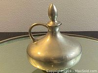 Front and handle view of a vintage Royal Holland pewter pitcher with a finial on the lid and handle.