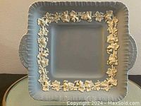 Front view of the square Wedgwood cake plate showing pale blue color, scalloped edge, and white vine relief motif.