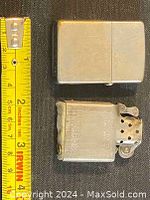 Top down photo showing closed Zippo lighter case and exposed insert next to a tape measure for size reference