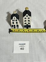 Two ceramic canal house bottles shown side-by-side with measuring tape, showing size and detail.
