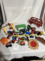 All items spread on white cloth backdrop showing various wooden train engines, cars, track pieces, and accessories.