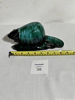 Side view of the green glazed Blue Mountain Pottery beaver figurine with measuring tape showing approximately 8 inches long.
