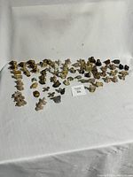 Wide angle view showing the entire collection of over 70 small ceramic figurines arranged on a white cloth background.