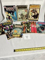 Photo showing 18 comics including Ghosts, Weird Mystery, Phantom Stranger laid out on a white surface with ruler