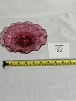 Top view of the cranberry glass dish showing scalloped ruffled edges and embossed ornate decorative pattern.