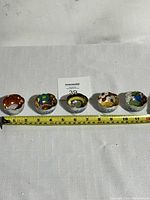 Top down photo showing the set of 5 small Japanese sake cups lined up side by side with tape measure displaying sizes