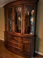 Front view of two-piece wooden dining hutch showing glass doors with decorative mullions, drawers and cabinet doors below