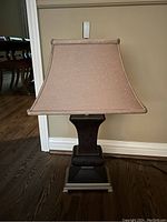 Full view of table lamp showing black textured base and light pink fabric lampshade