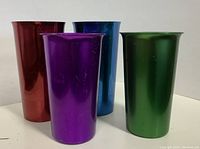 Four vintage aluminum tumblers in red, purple, blue, and green metallic finishes.