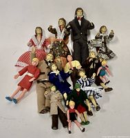 Top view of group of 17 vintage miniature dolls in various period clothing.