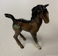Front-side view of the glossy brown and black Beswick foal horse figurine standing upright with label visible on the side.