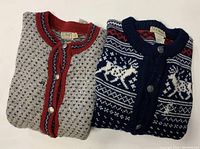 Two folded vintage LL Bean wool sweaters, one gray with red and blue trim, other navy blue with white and red Norway knit patterns and animal motifs