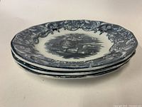 Stacked view of three antique flow blue dinner plates showing side profile and rim detail