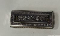 Top side of vintage Echo Hohner harmonica showing M. Hohner branding and decorative engraving.
