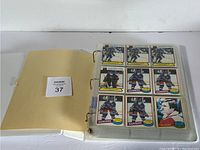 Open binder showing clear plastic pages with nine O-Pee-Chee 1980-81 hockey cards per page featuring various players