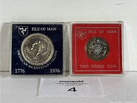 Two Isle of Man coins in cases side by side, showing front design and coin details.