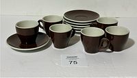 Full set of six brown espresso cups each paired with a saucer, displayed on a white surface.