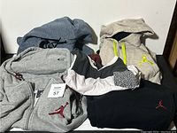 Five Jordan brand clothing items displayed: three hoodies, one pair of pants, one shirt.