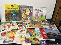 Various children's books arranged on floor, titles visible include Flik the Inventor, Vacation!, The Bird & the Hippo, Apple Pie ABC, Mole in the Hole, Snake and the Birds, and others.