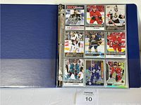 Open blue binder showing a page with 9 NHL rookie hockey cards in protective sleeves.