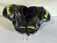Front view of black Riddell Surge youth small football shoulder pads, showing yellow branding and lace-up front.