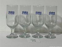 Four clear stemmed glasses with 'Stelco No. 2 Rod Mill' logo in blue on each.