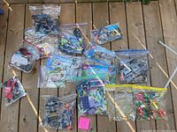 Full overview of the assorted Lego pieces packed in zip-lock bags on a wooden floor, showing multiple sets including Lego Friends, Star Wars, and Lego China.