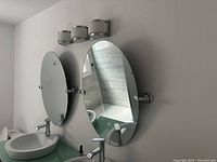 Oval bathroom mirror installed on wall above sink and under light fixture, showing reflective surface and mounting hardware.