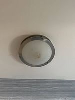 Front view of circular ceiling light fixture mounted flush to ceiling showing frosted glass diffuser and silver metal trim