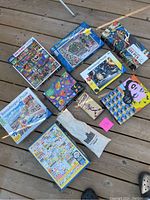 Photo showing all puzzles and game for the lot, including a Marilyn Monroe Andy Warhol double-sided puzzle and various other Ravensburger puzzles ranging from 300 to 1000 pieces.