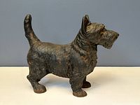 Side view of antique cast iron Scottish Terrier dog door stop showing textured surface and raised tail.