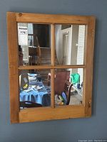 Front view of the antique pine window frame mirror mounted on a wall reflecting a dining area.