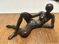 Photo showing the nude woman sculpture lying on its side with bent knees and one arm supporting the body.