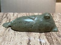 Front side view of entire seal sculpture lying on marble surface