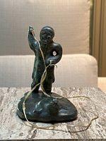 Front view of soapstone sculpture showing hunter raising raffia line with seal at base