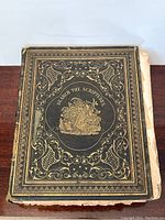 Front cover of large antique family Bible with ornate gold embossing and text 'Search The Scriptures'