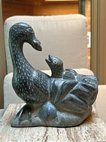 Front-quarter view of soapstone carving showing goose profile and chick in nest