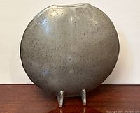 Front view of round pottery vase with attached stand, showing full shape and speckled glaze.
