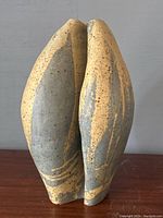 Front view of the pottery vase showing the beige and gray speckled glaze and sculptural shape.