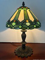 Full view of Tiffany style lamp showing overall design and color of stained glass shade and detailed bronze-like base