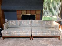 Front view of two piece sectional sofa placed against fireplace, showing overall shape, upholstery pattern and wooden base.