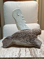 Overall view of the sculpture showing the seal base and the abstract face figure on top