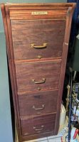 Front view of the 1920s wooden filing cabinet showing four drawers with brass handles and keyholes.