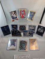 Photo taken showing a selection of 14 hockey cards on display including rookie, numbered, and various all-star cards featuring Elias Pettersson, Henrik Sedin, Quinn Hughes, and others. Cards are held in plastic sleeves.