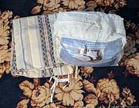 Photo of the feather and down duvet in its original white storage bag along with the folded West Elm patterned duvet cover lying next to it on a floral carpet.