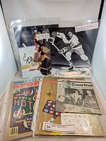 Autographed photos, collectible sports magazines and newspaper clipping arranged together, visible signatures of Garry Monahan and Garth Butcher on photos.