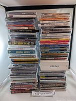 Stacks of sealed music CDs showing titles and colorful jewel case covers.