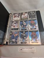 Open binder page showing nine different modern hockey trading cards in clear plastic pockets, featuring eight players with different teams and poses.